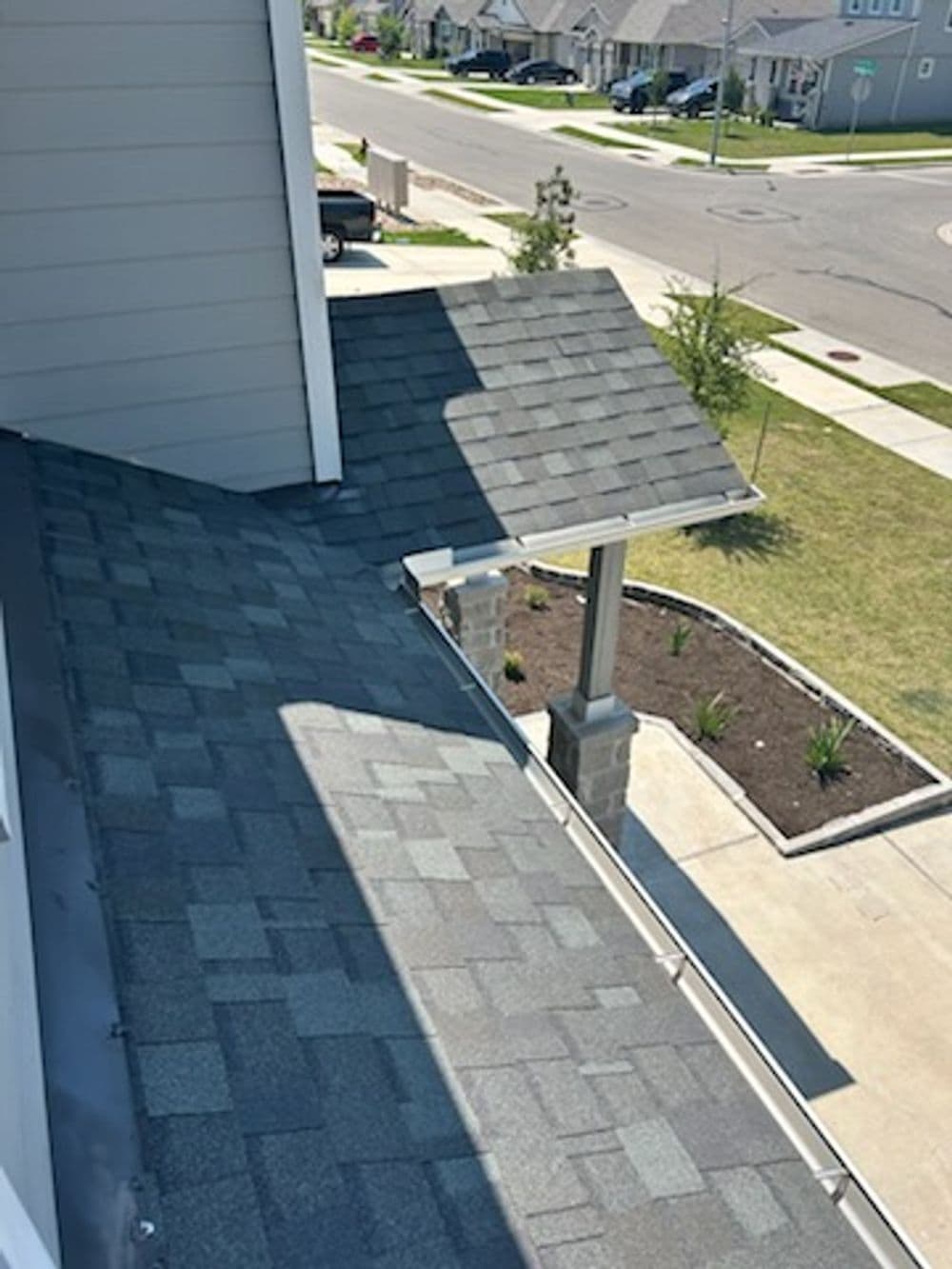 Bird's-eye view of a house roof with gray shingles and a well-maintained yard.
