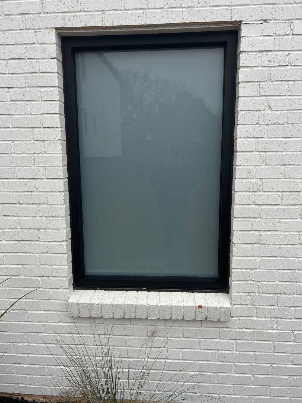 Frosted glass window on a white brick wall with a minimalist design.