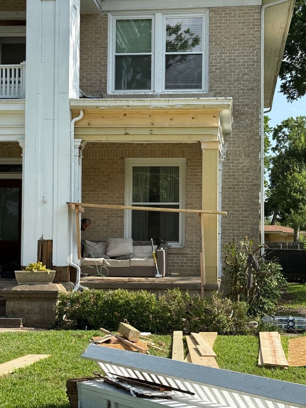 Renovation project at a historic home with construction materials and a worker on the porch.