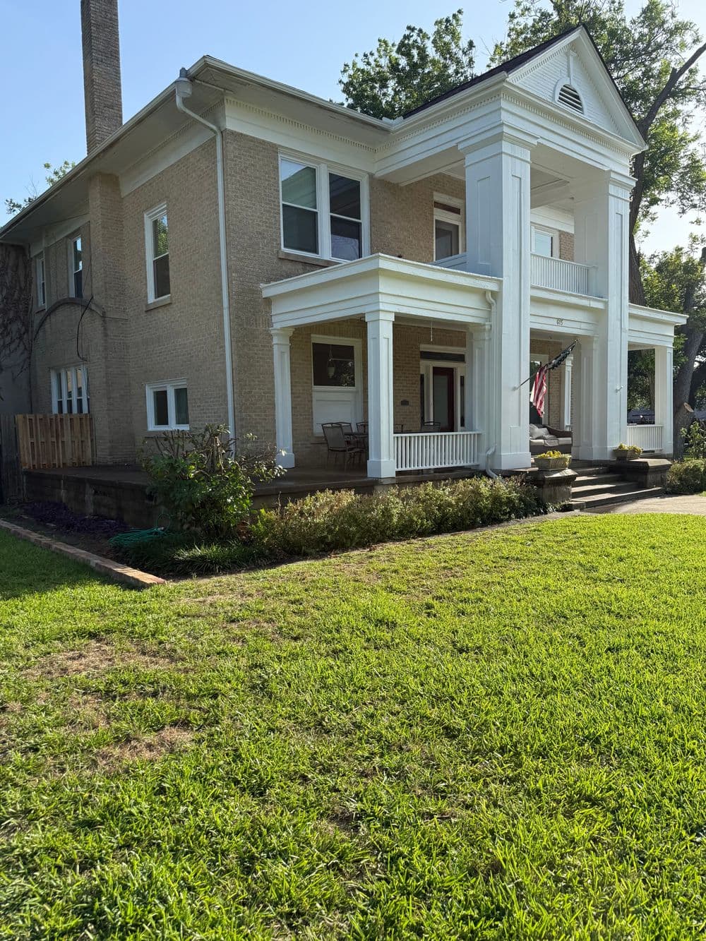 Elegant two-story home with white pillars, large porch, and lush green lawn.