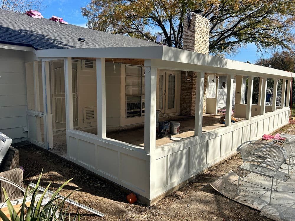 Newly constructed sunroom with a stone fireplace and large windows, surrounded by a garden.
