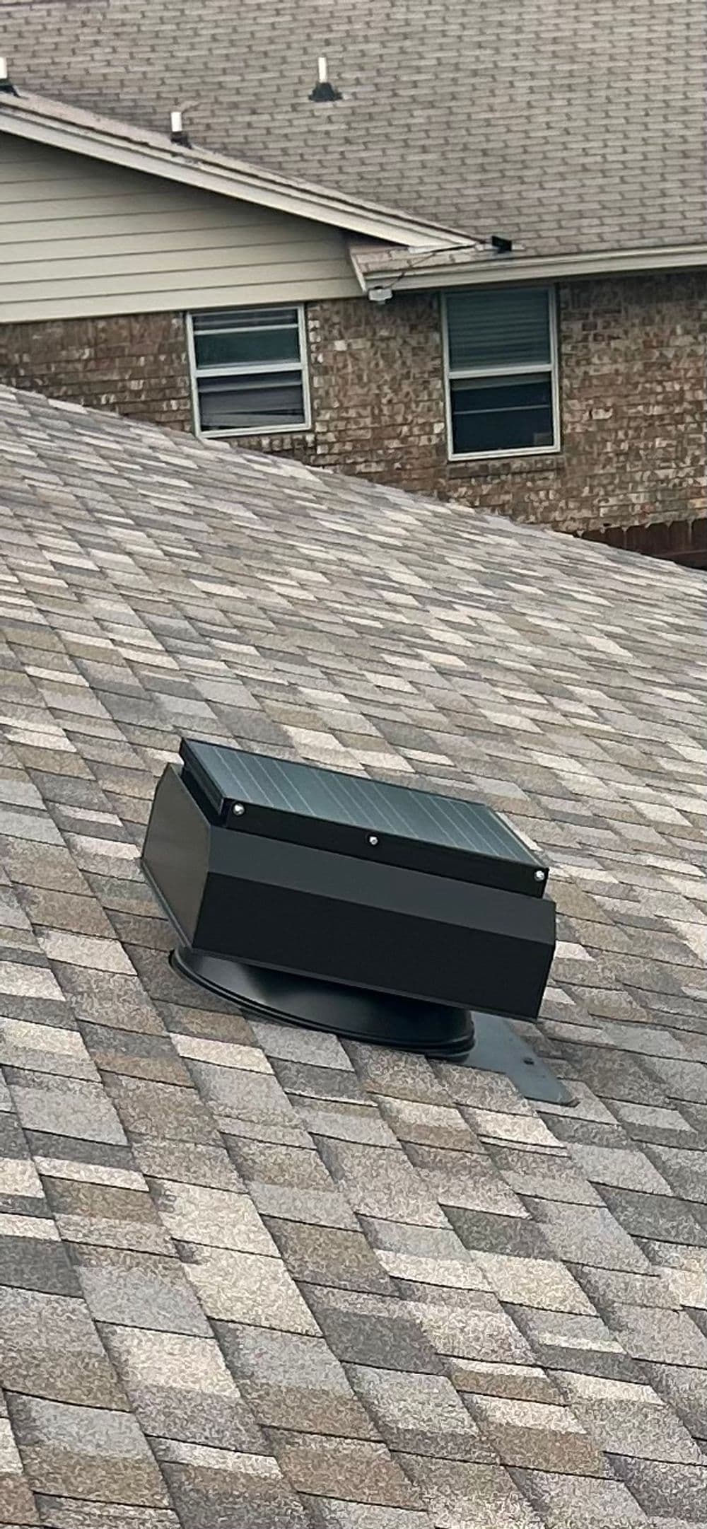 Solar attic fan installed on shingle roof for improved ventilation and energy efficiency.