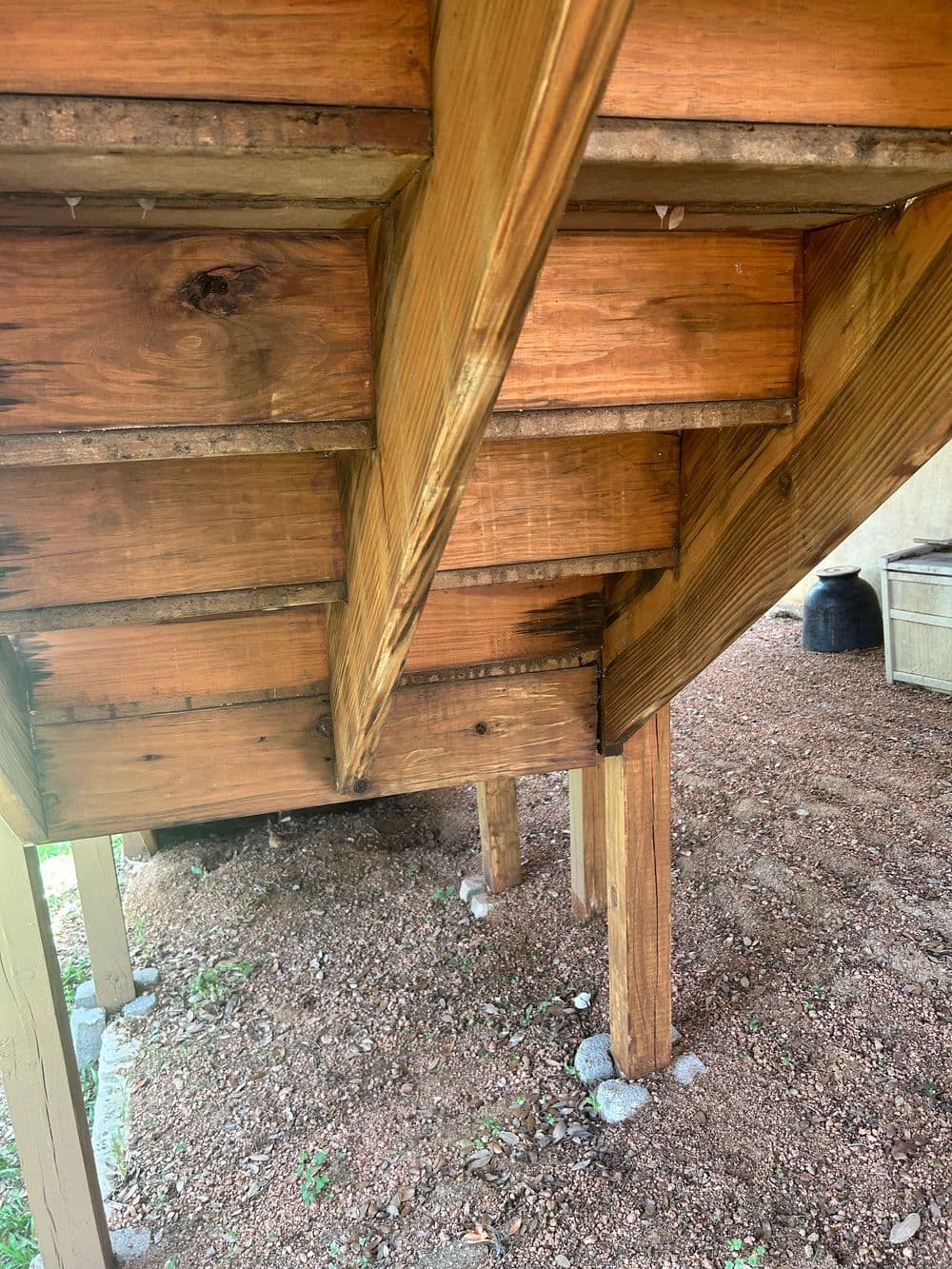 Wooden beams and supports under a structure, showcasing construction details and natural textures.