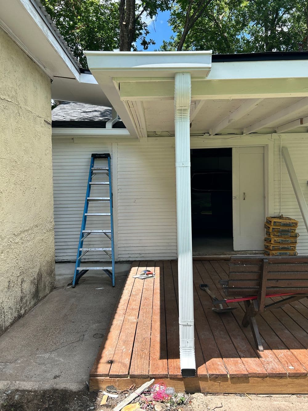 Ladder and wooden deck under a house porch, ready for renovation.