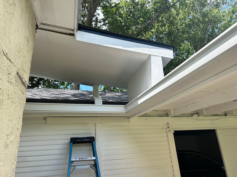 View of a residential roof renovation showing new overhang and ladder in sunlight.