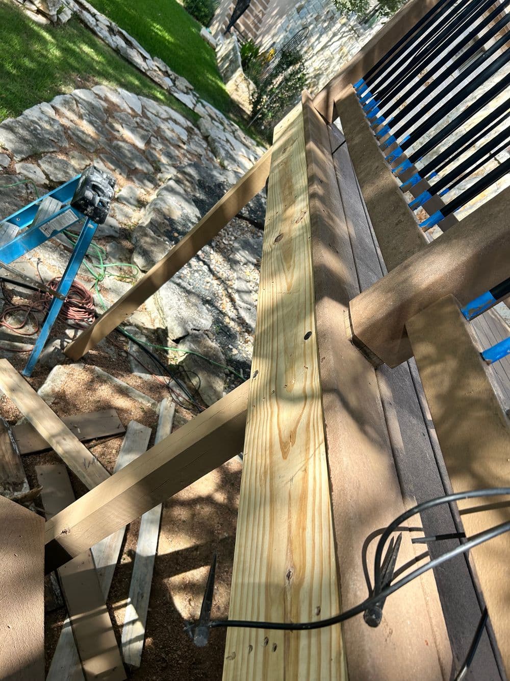 Construction of a wooden deck with framing and tools in a backyard setting.