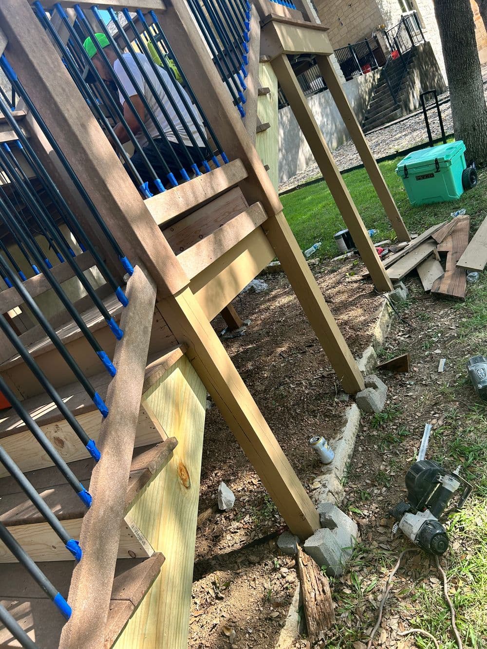 Construction of a wooden staircase with railings, tools, and materials in a yard setting.